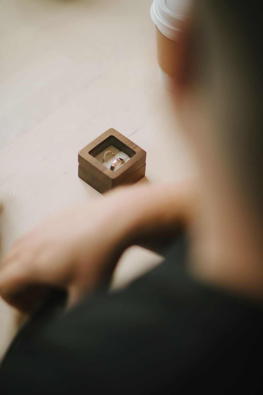 Elegant gold and ruby wedding bands displayed in a wooden ring box on a neutral surface with soft natural lighting