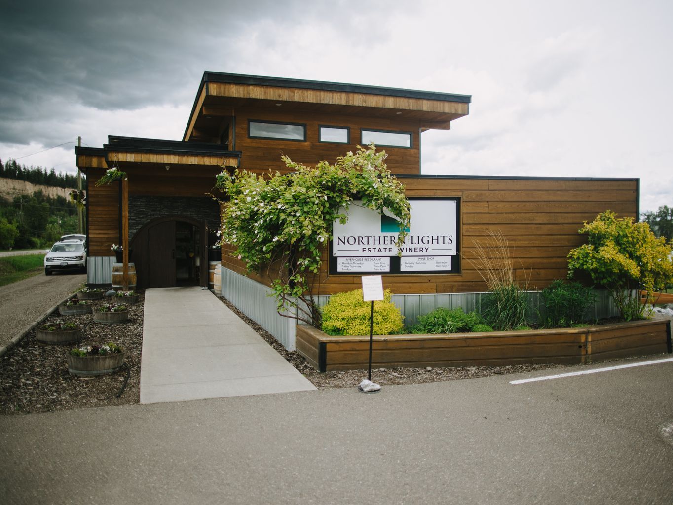 Northern Lights Estate Winery entrance with wooden architecture, lush green vines, and signage under cloudy skies