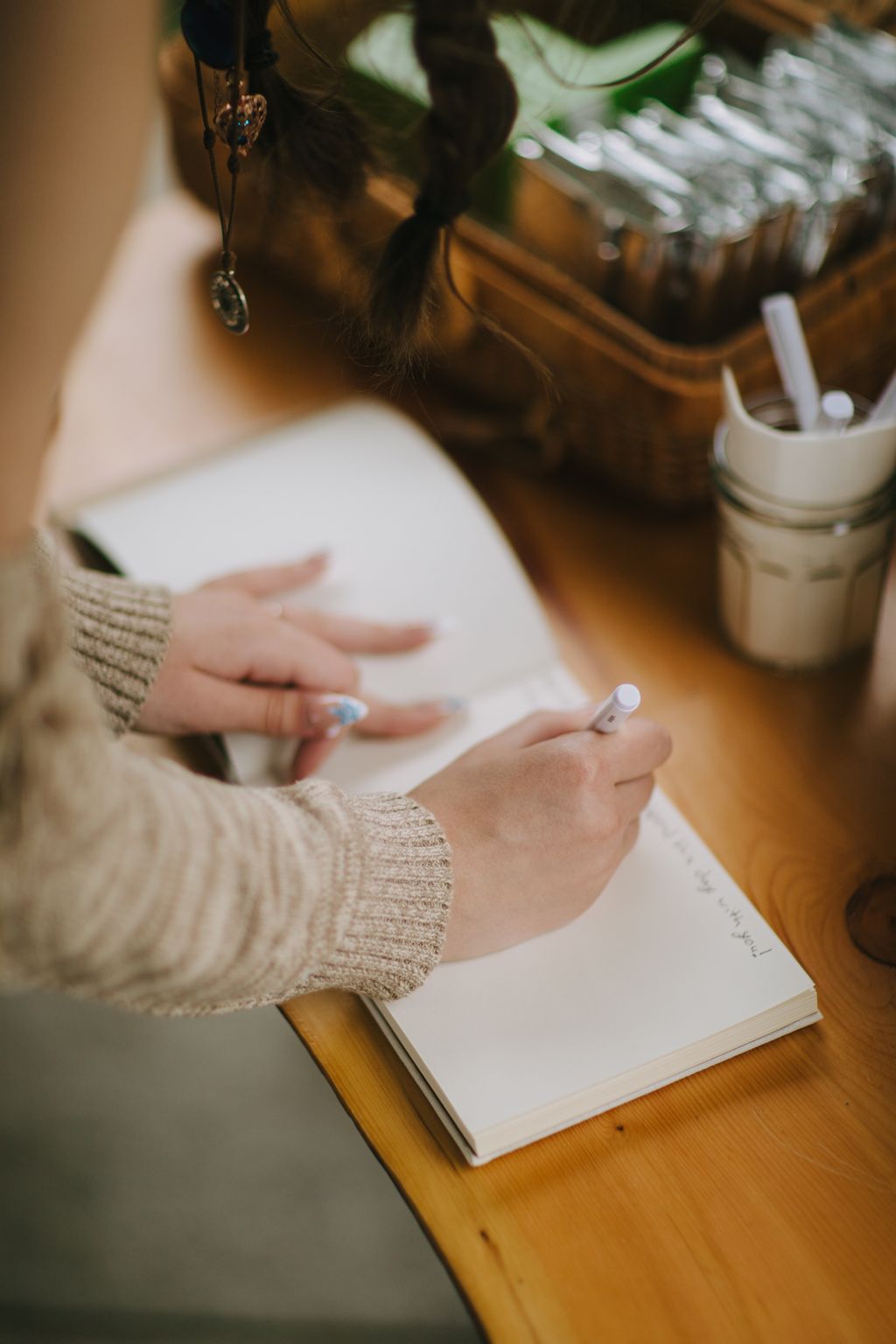 Bride''s hands holding positive pregnancy test over open book, wearing cream sweater and ring, warm wooden table setting