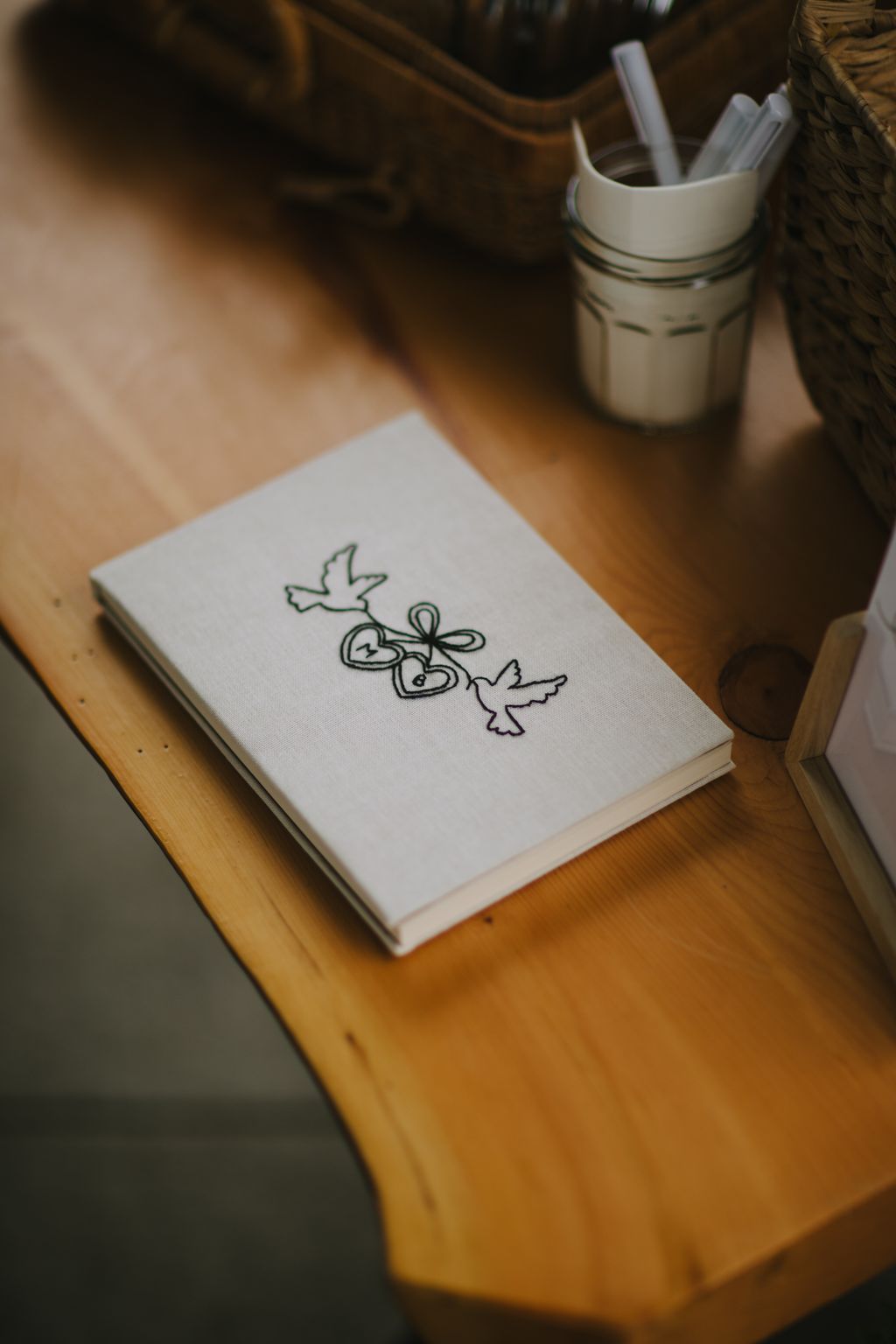 Artistic line drawing of doves and hearts on white paper resting on warm wooden surface with ceramic cup nearby