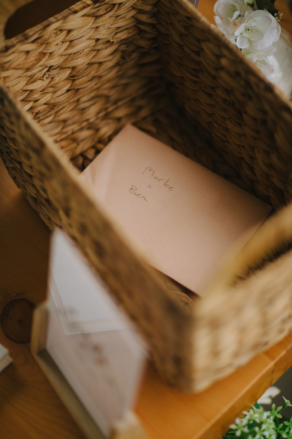 Handwritten names "Marlee + Ben" on pale skin beneath flowing golden-brown hair in warm, intimate lighting