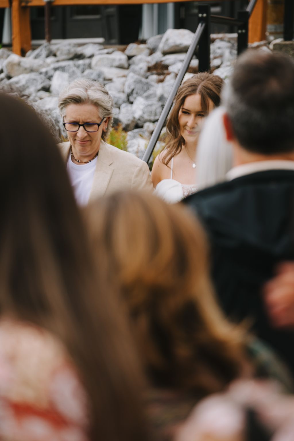 Bride and groom smile during outdoor ceremony with stone wall backdrop and natural light