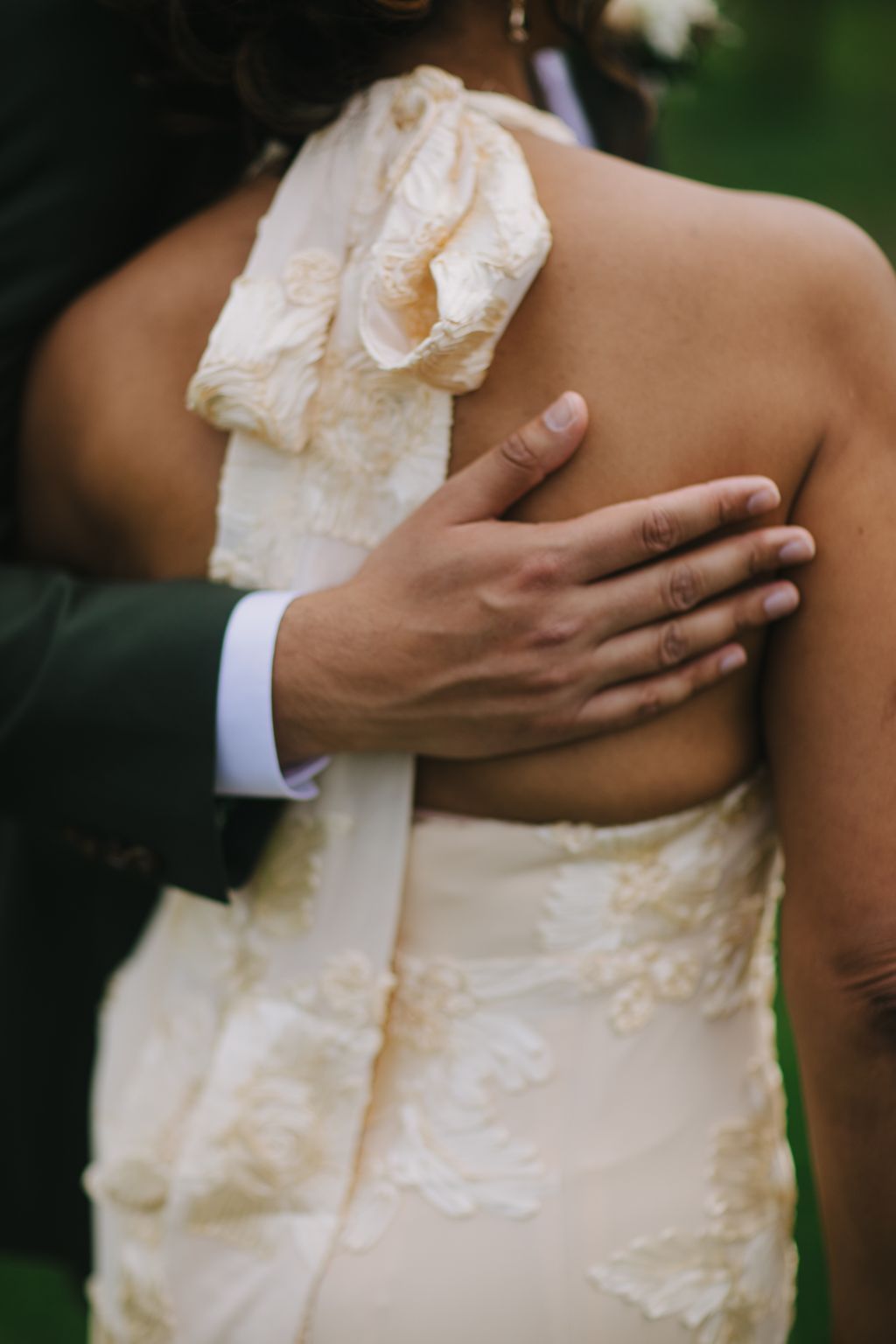 Groom''s hand rests on bride''s lace-detailed wedding dress in an intimate moment of connection