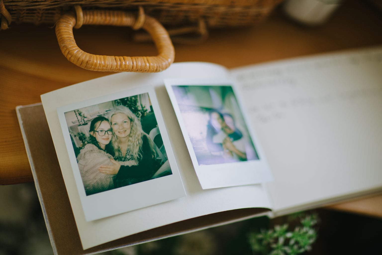Instant film photographs scattered on a white surface with woven basket detail in warm, natural light