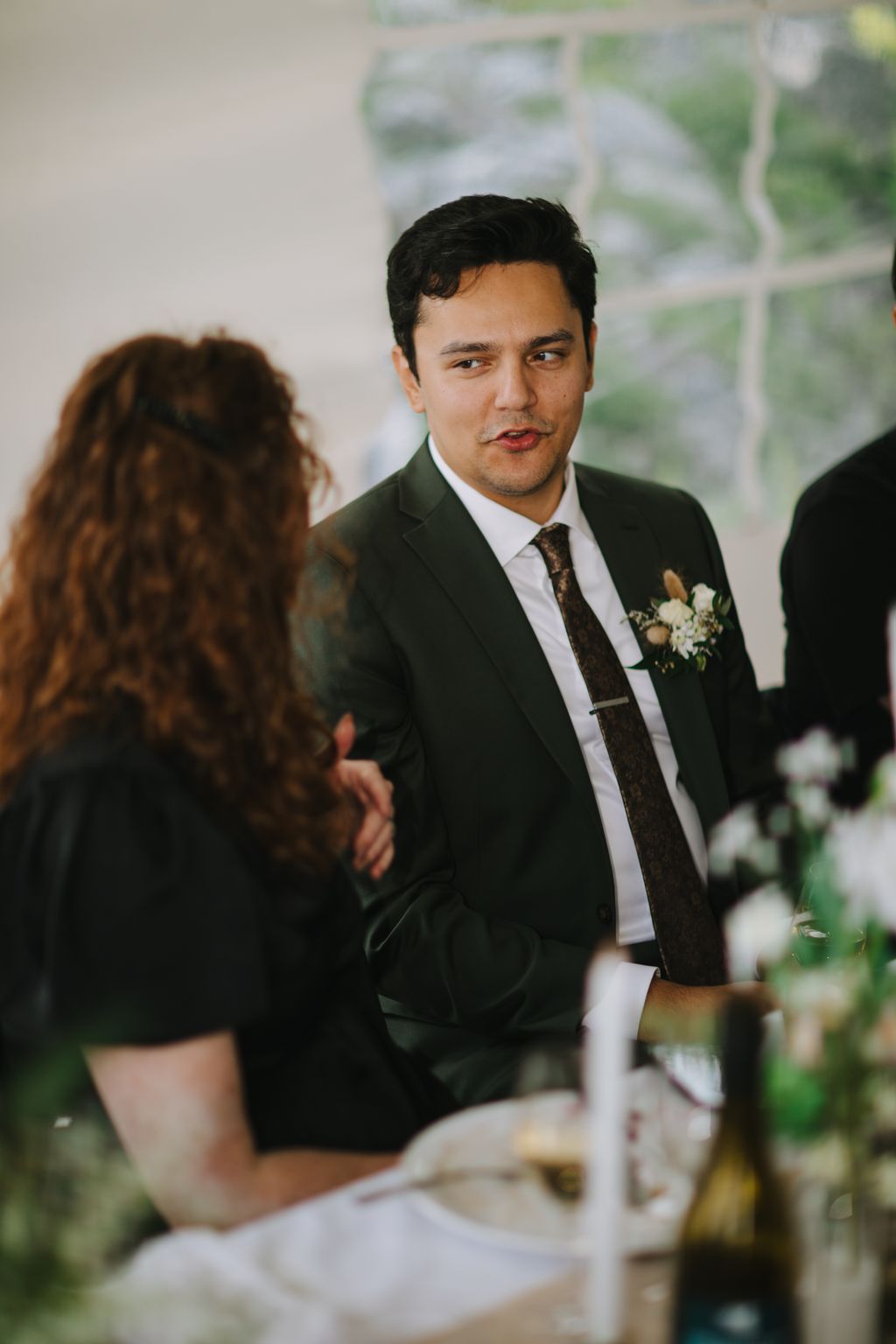 Groom in dark suit and patterned tie gazes at bride during intimate wedding ceremony moment