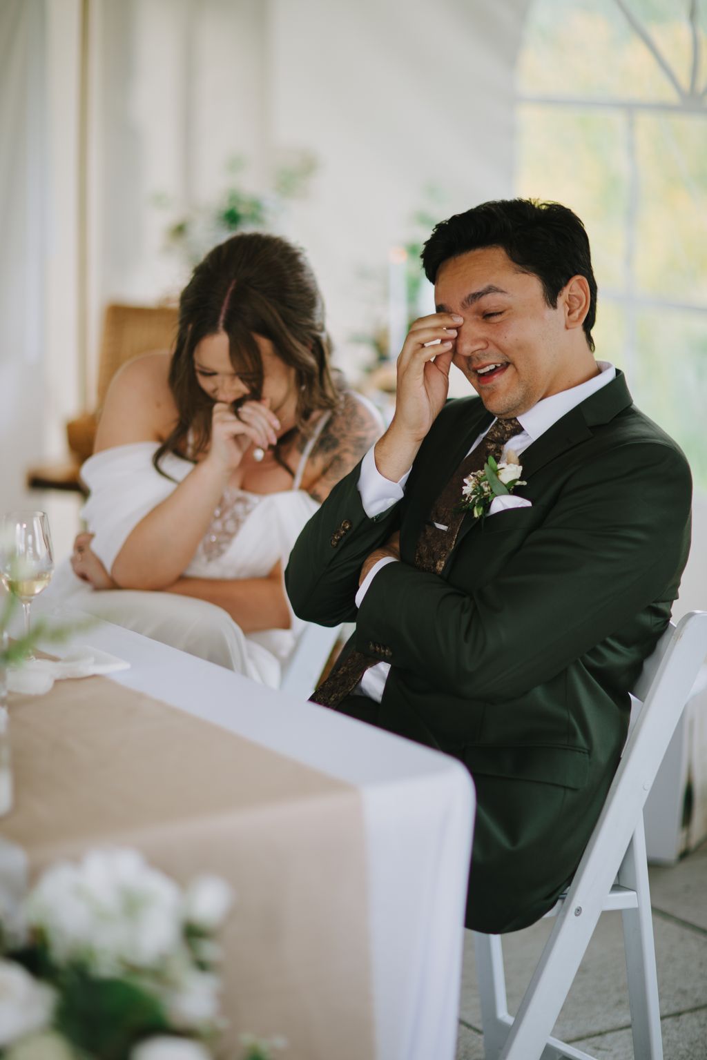 Groom wipes away tears of joy while bride smiles beside him during emotional wedding ceremony moment