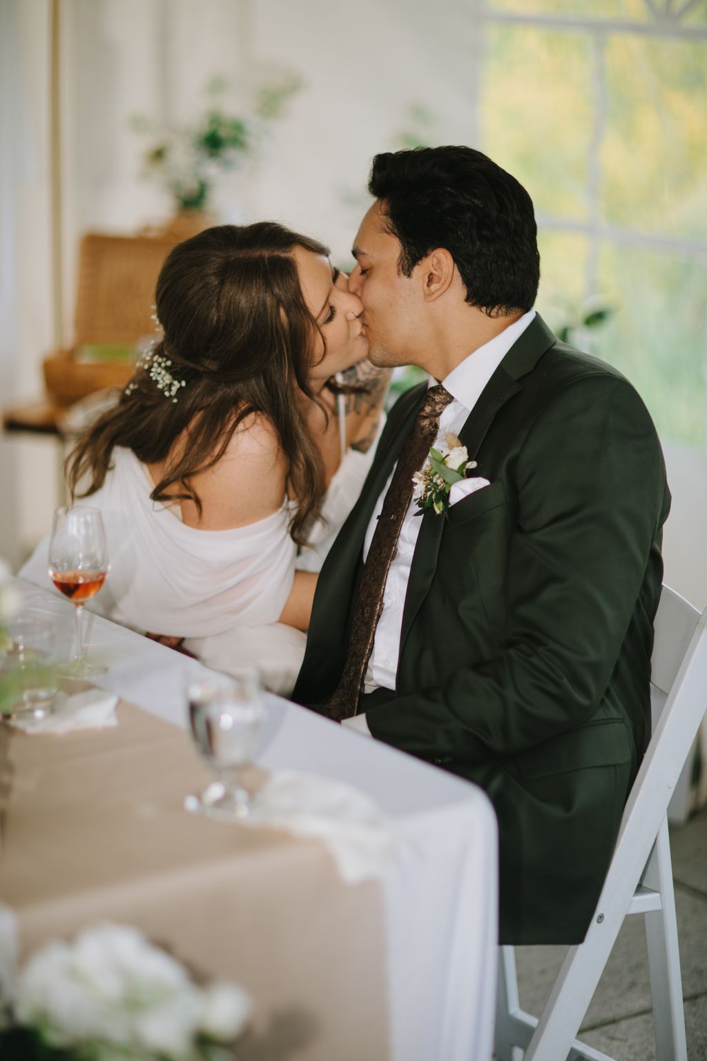 Bride and groom share a kiss at the altar during their wedding ceremony, soft natural light illuminating their intimate moment