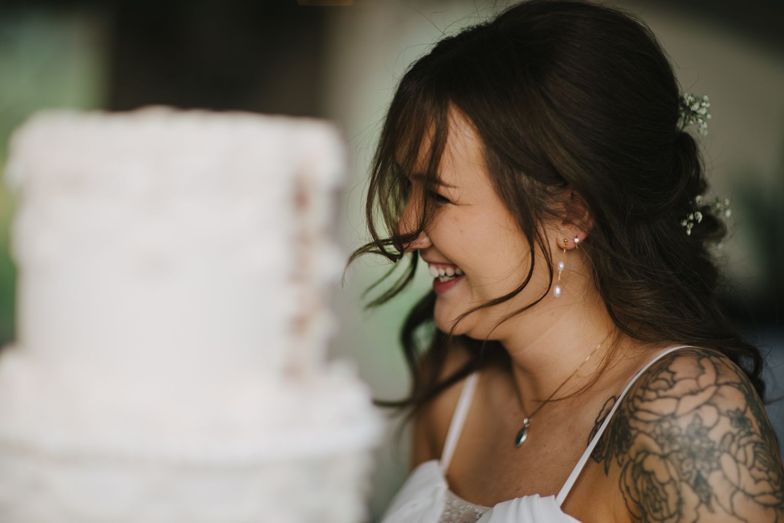 Smiling woman in profile with dark hair backlit by soft natural light, wearing white, blurred background