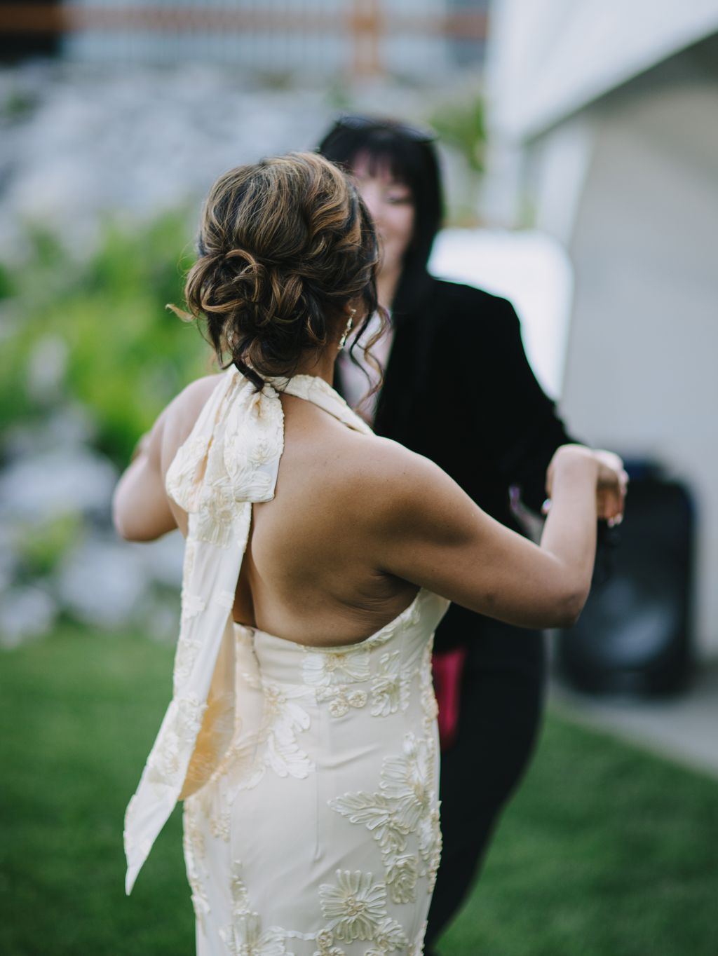 Bride in ivory beaded gown with elegant updo hairstyle stands outdoors during wedding ceremony