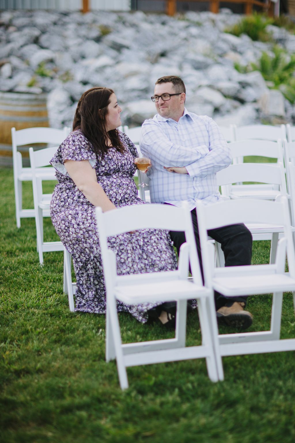 Couple in purple floral dress and light blue shirt holding champagne glasses at outdoor garden reception