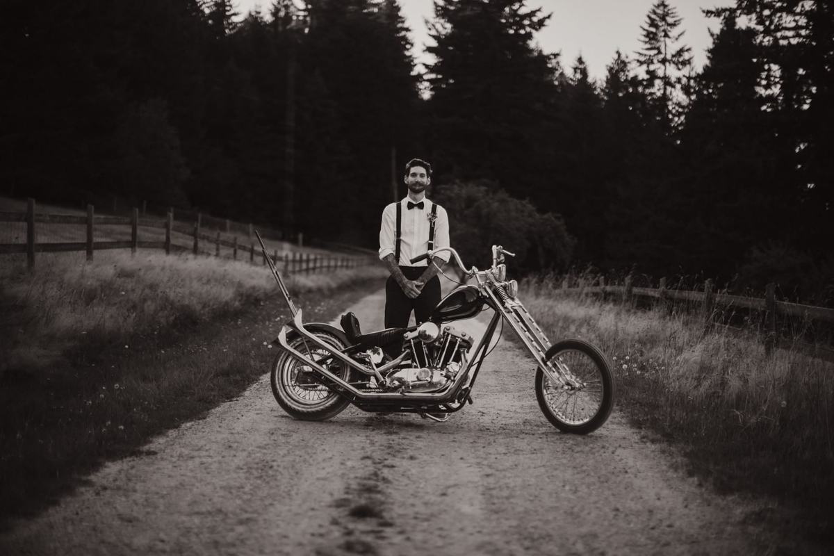 Groom standing beside a vintage motorcycle