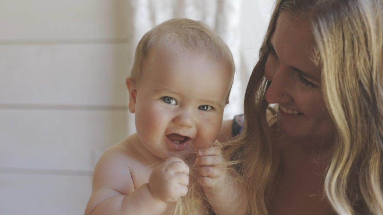 Laughing toddler grasps woman's long hair during a candid moment at Bullock Lake Farm wedding