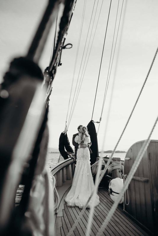 Couple embracing at the bow, framed down the rope-lined deck