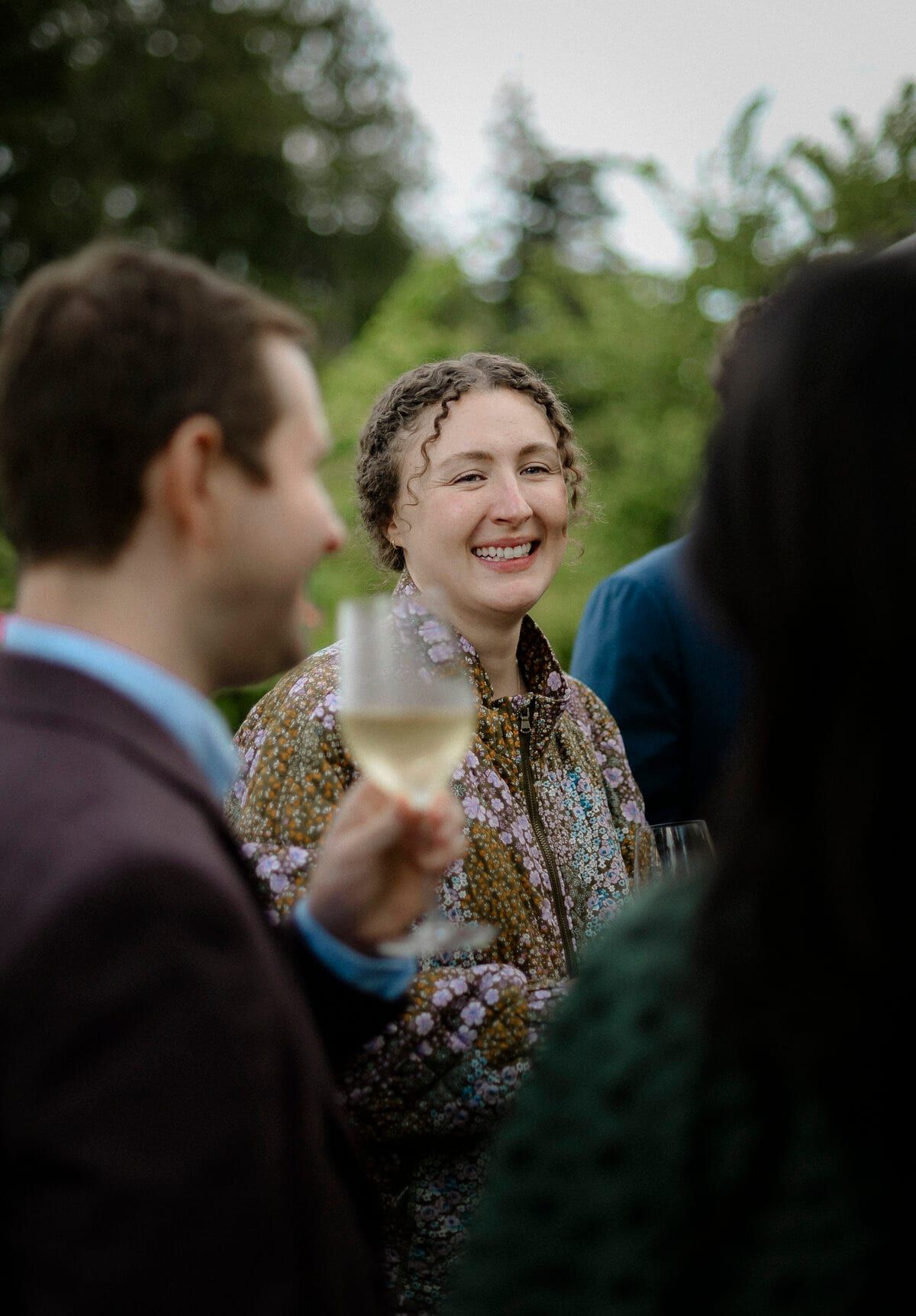 Curly-haired guest smiling with a glass of white wine