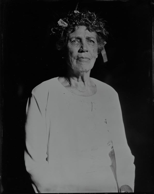 Elderly woman wearing a flower wreath, wet-plate portrait