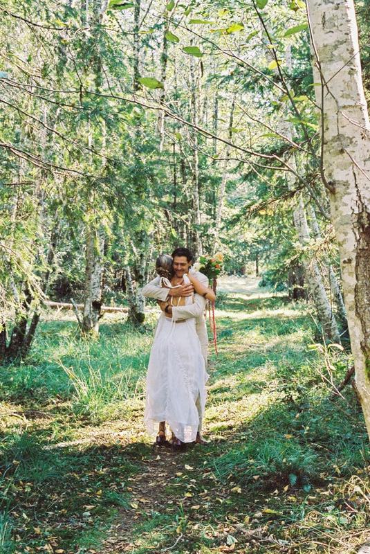 Couple hugging tightly on a sunlit trail between slender birch trees