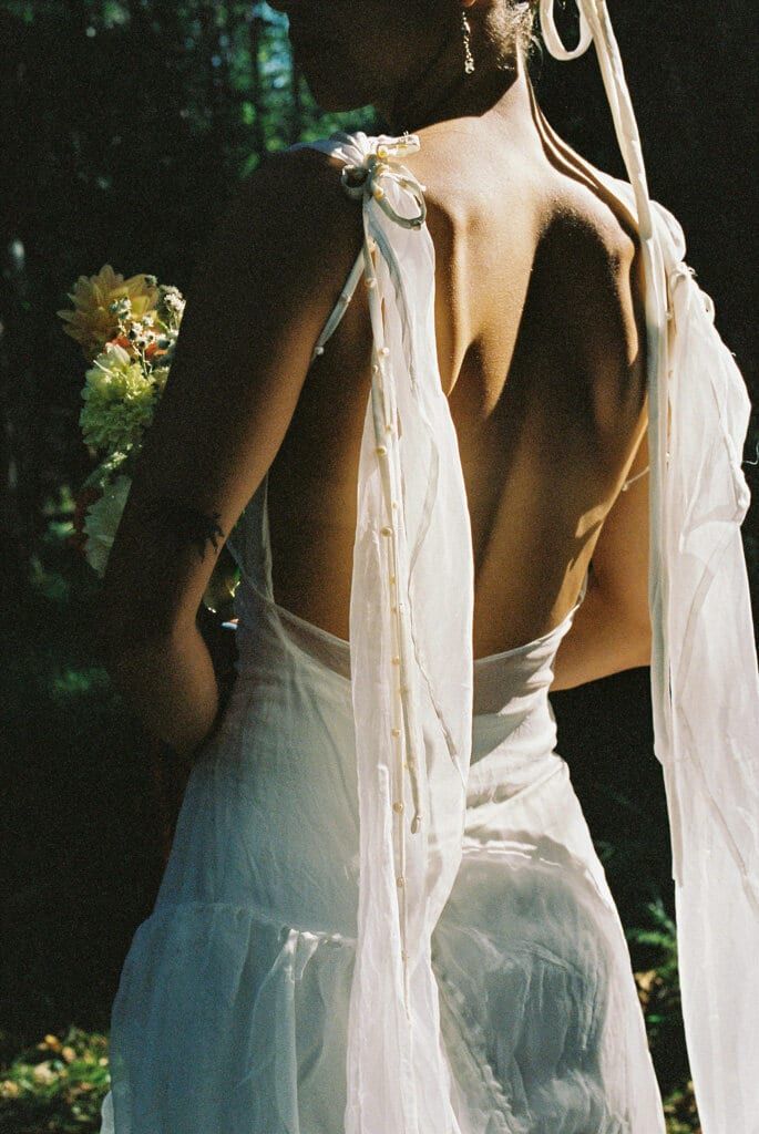 Ribbon-tied open back of a bridal gown in dappled sunlight