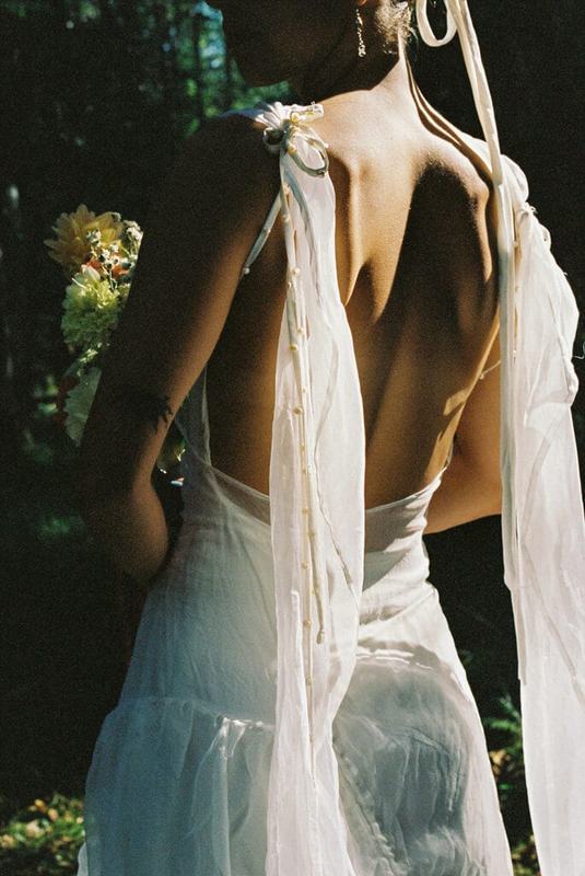 Ribbon-tied open back of a bridal gown in dappled sunlight