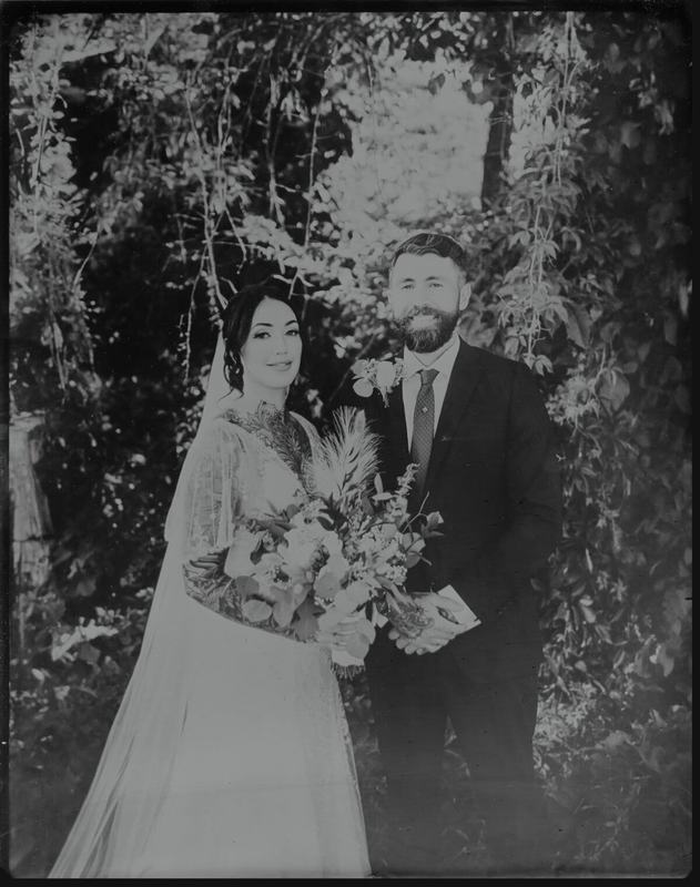 Tintype of smiling newlyweds beneath trailing vines