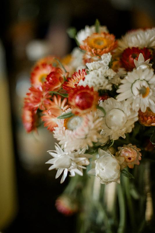 Bouquet of orange and white strawflowers and daisies in soft light