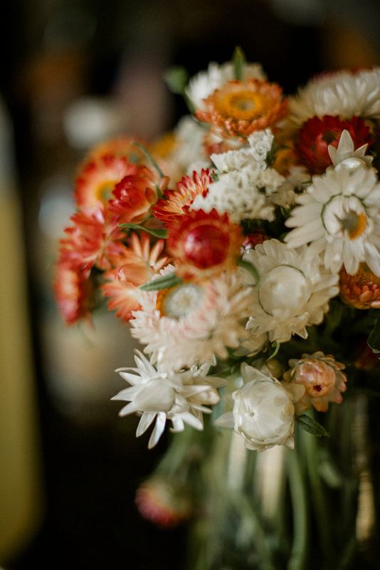 Bouquet of orange and white strawflowers and daisies in soft light