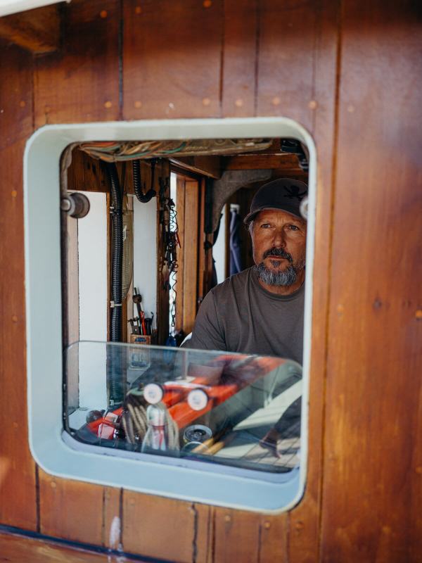 Bearded skipper looking out through the wooden wheelhouse window