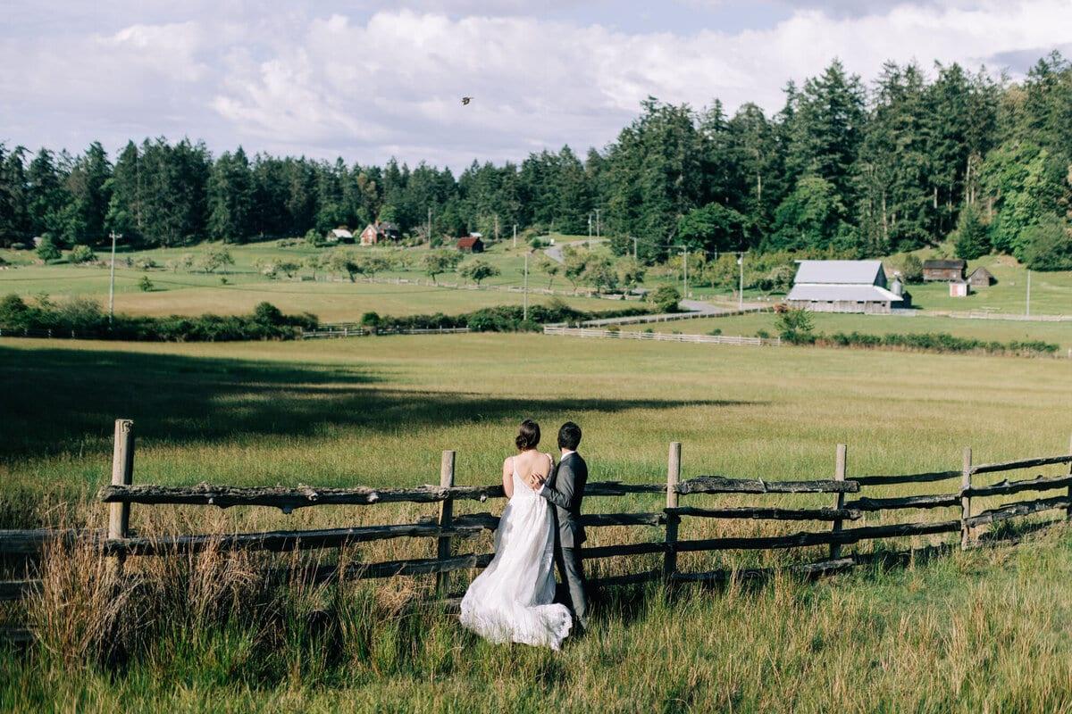 Couple leaning on a split-rail fence overlooking green island farmland
