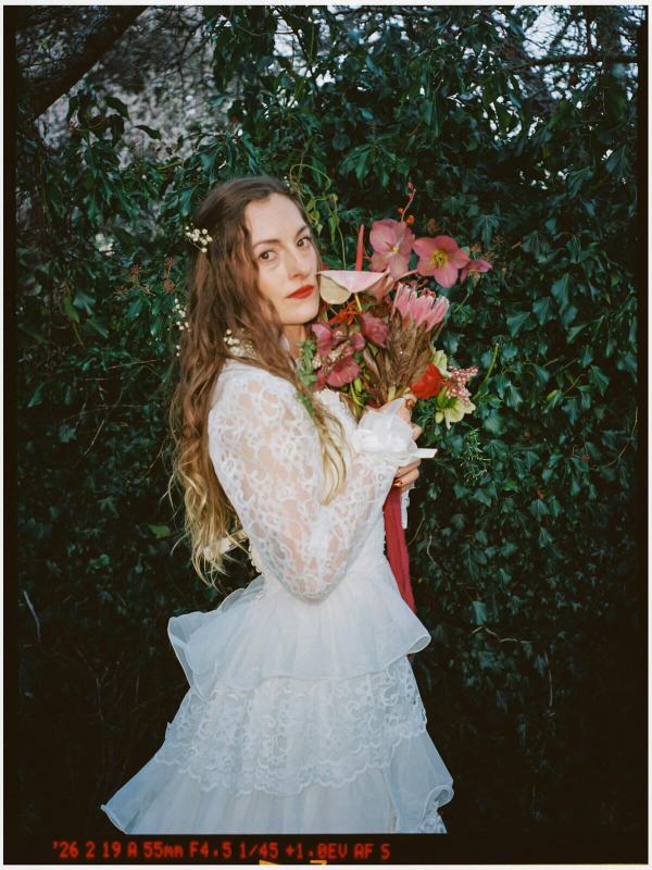 Bride in vintage lace holding pink blooms on a 35mm film frame