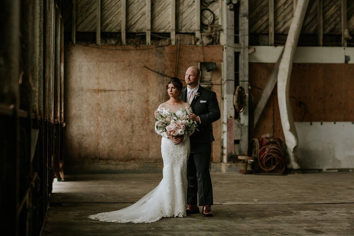 Bride and groom posed inside a weathered old barn