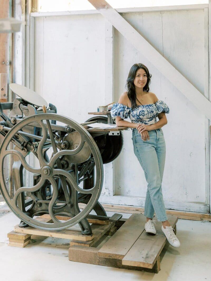 The AYLA View artisan beside a vintage letterpress machine