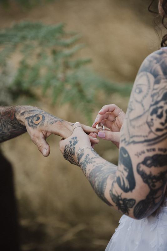 Close-up of tattooed hands sliding on a wedding ring