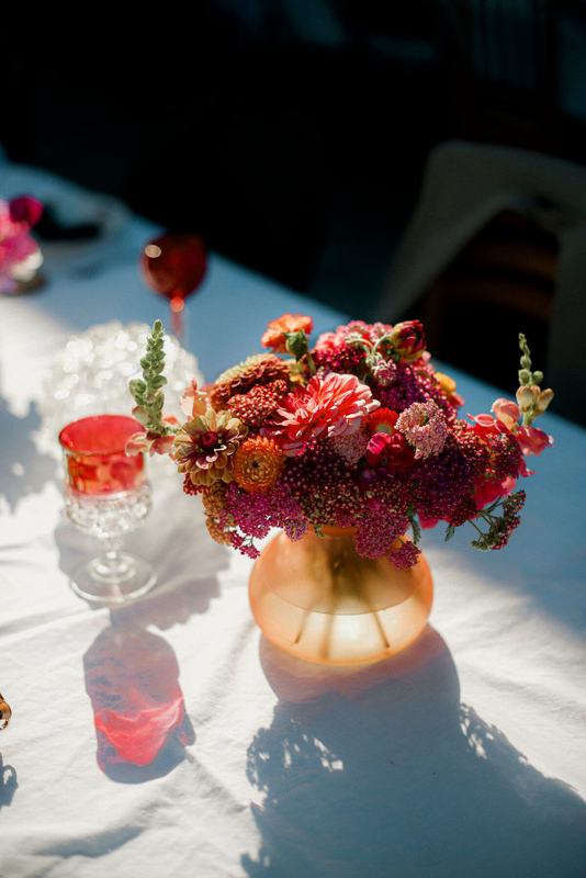 Sunlit centrepiece of red and pink dahlias on white linen