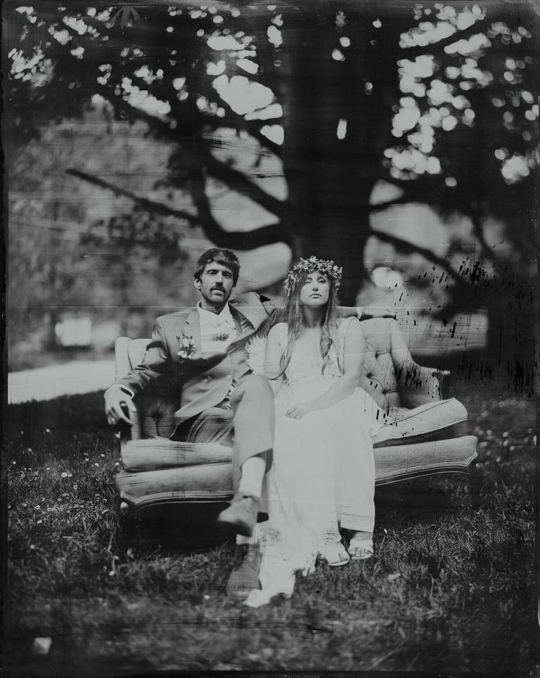 Tintype of a couple seated on a vintage sofa beneath a tree