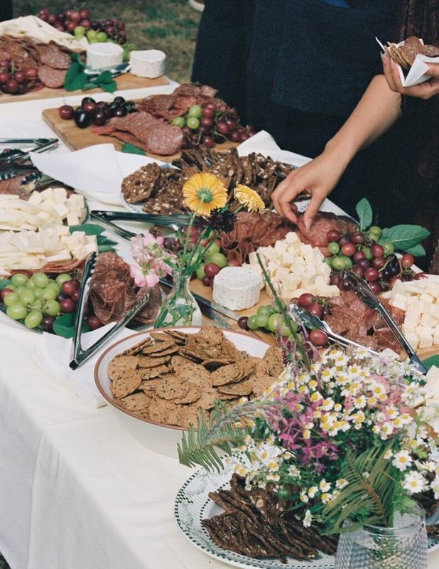 Grazing table piled with cheese, charcuterie and wildflowers at the reception