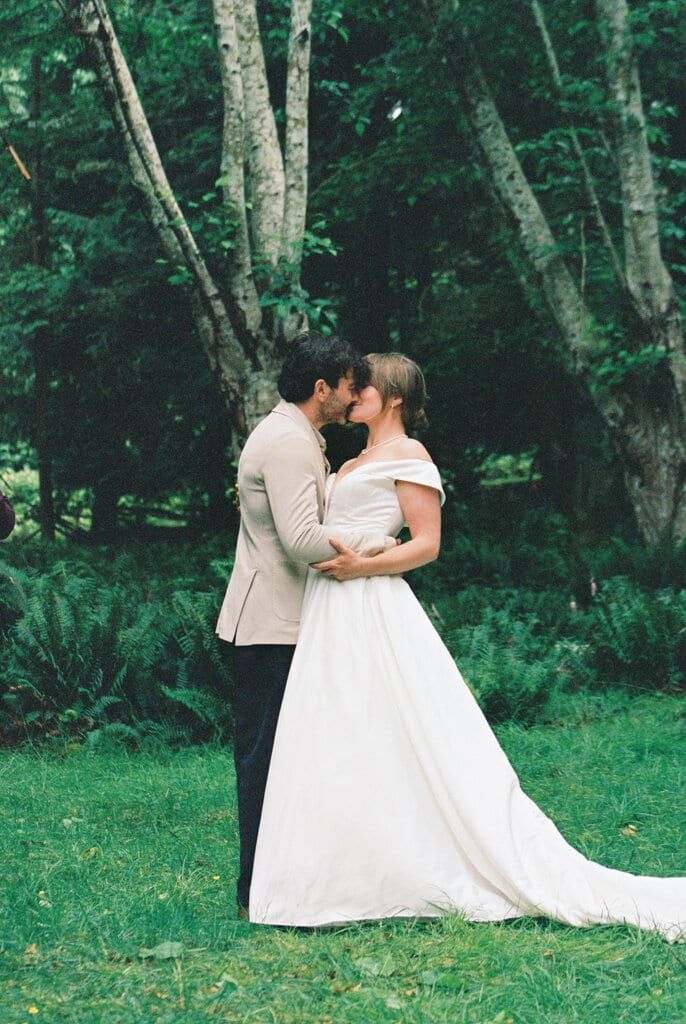 Couple sharing a quiet kiss among mossy birch trunks