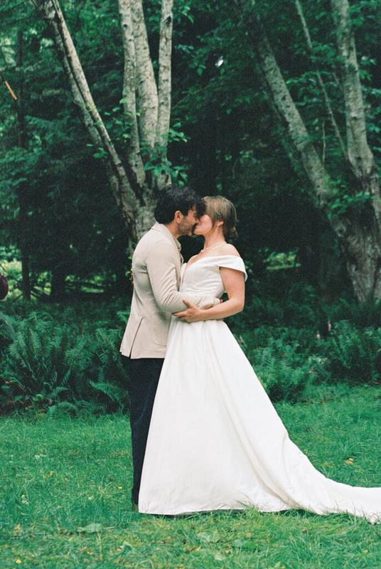 Couple embracing nose to nose in a lush green forest clearing