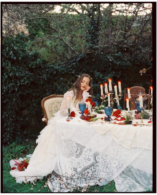Bride seated at a lace-draped garden table lit by candelabras