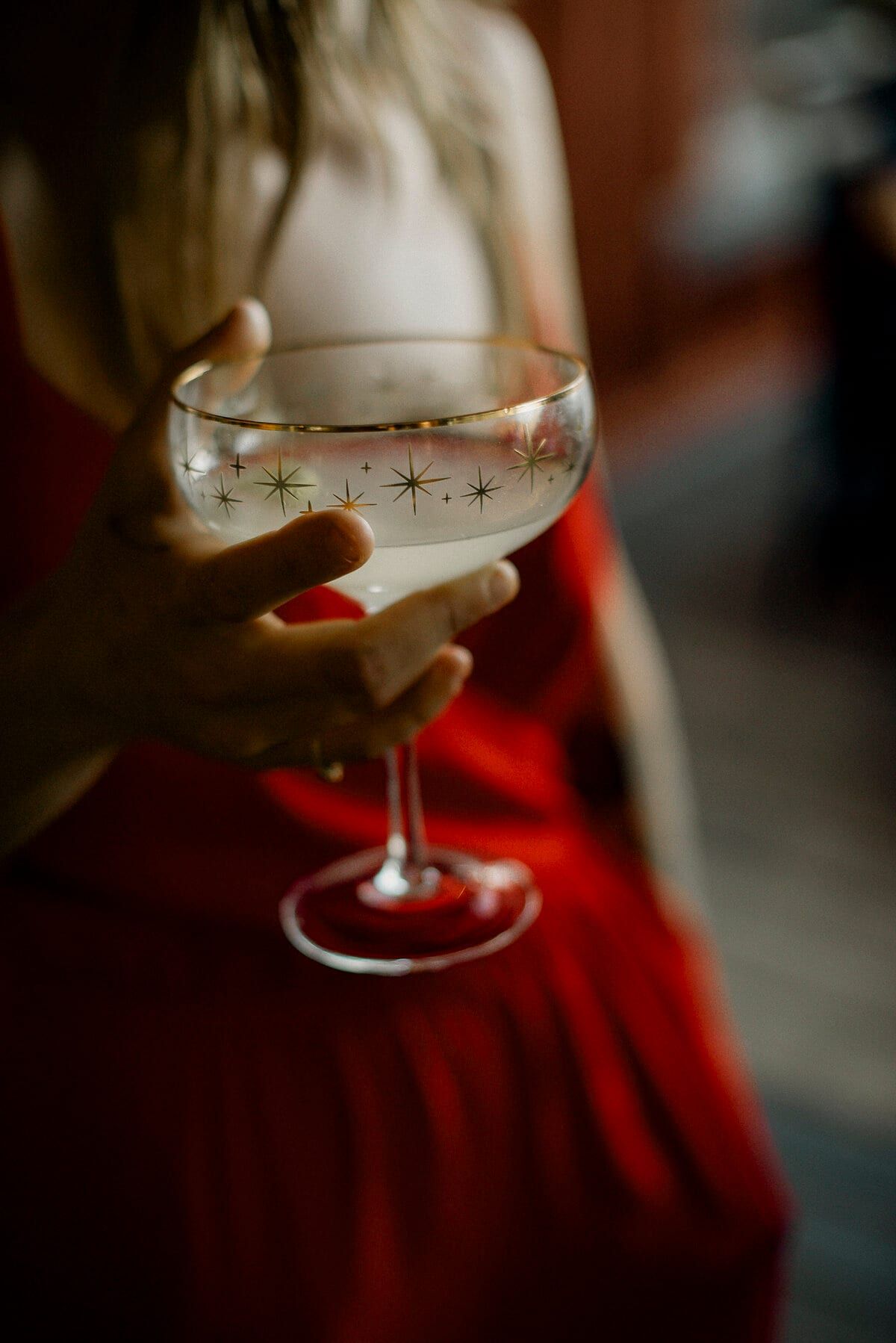 Guest in a red dress holding a starburst-etched coupe glass