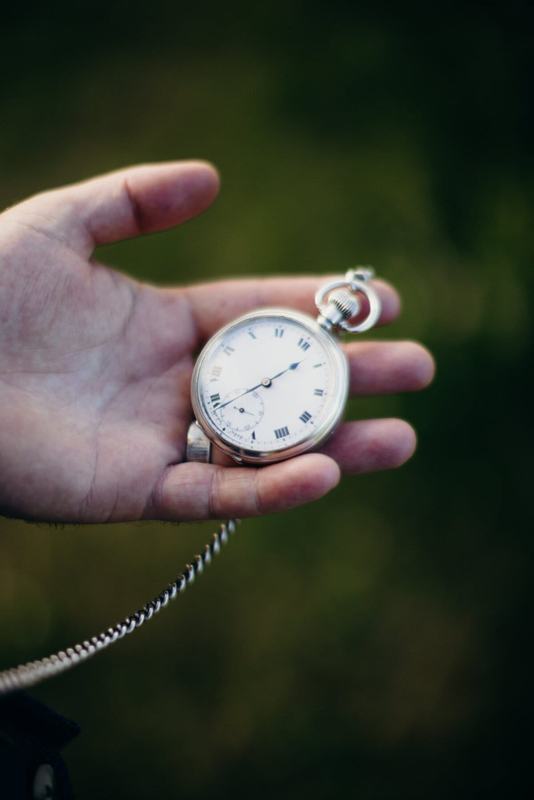 Open hand holding a vintage pocket watch on a chain