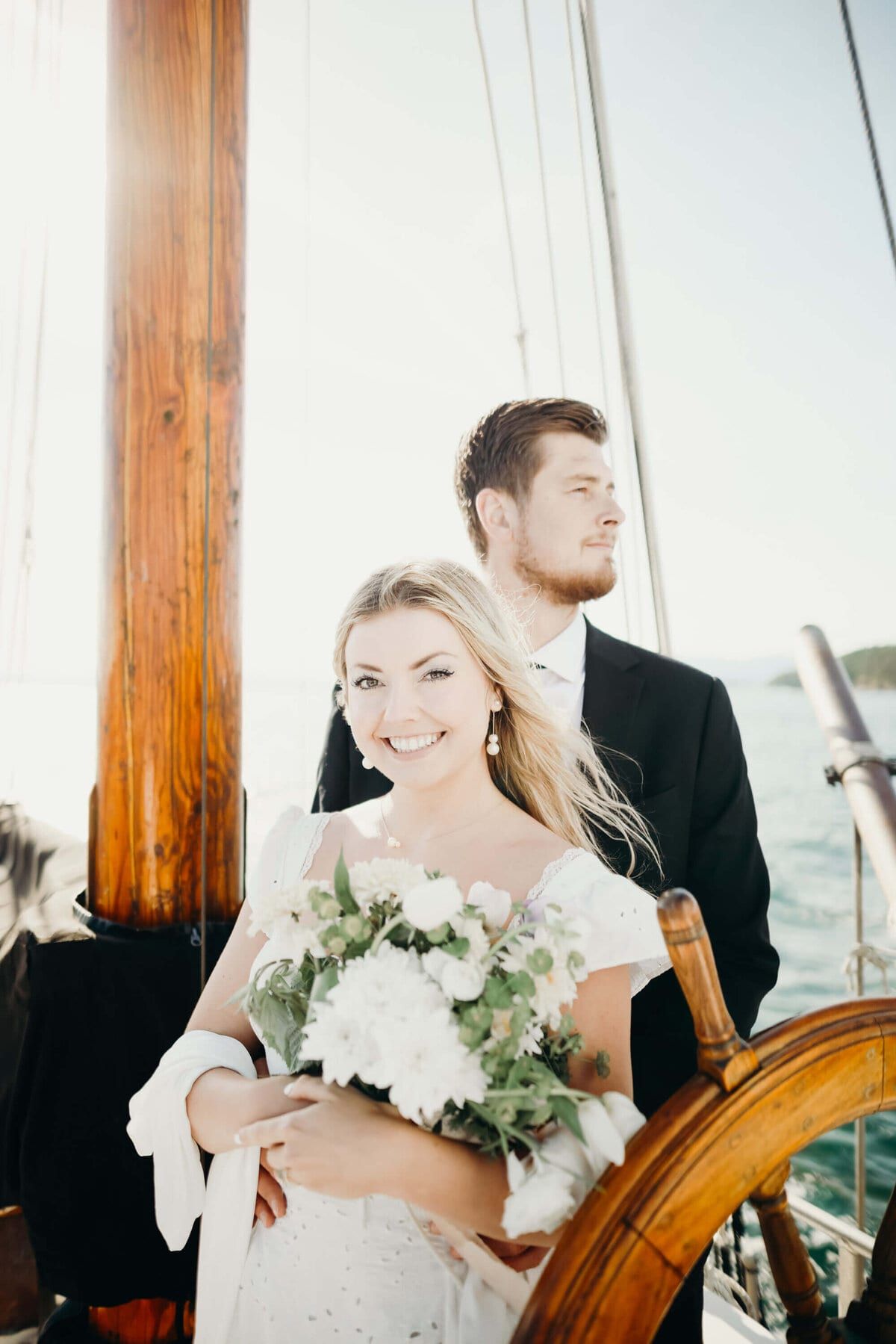 Smiling bride with a white bouquet standing at the helm