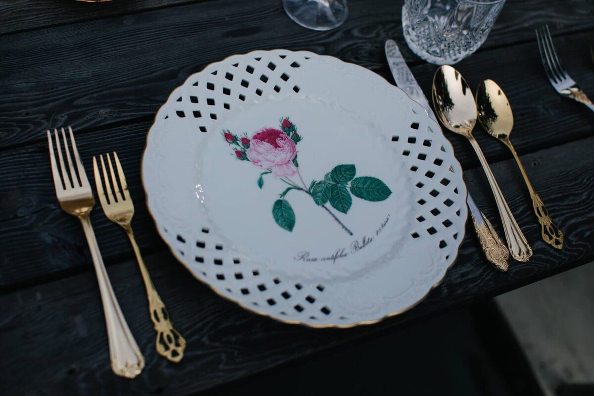 Lattice-edged botanical plate flanked by gold forks and spoons