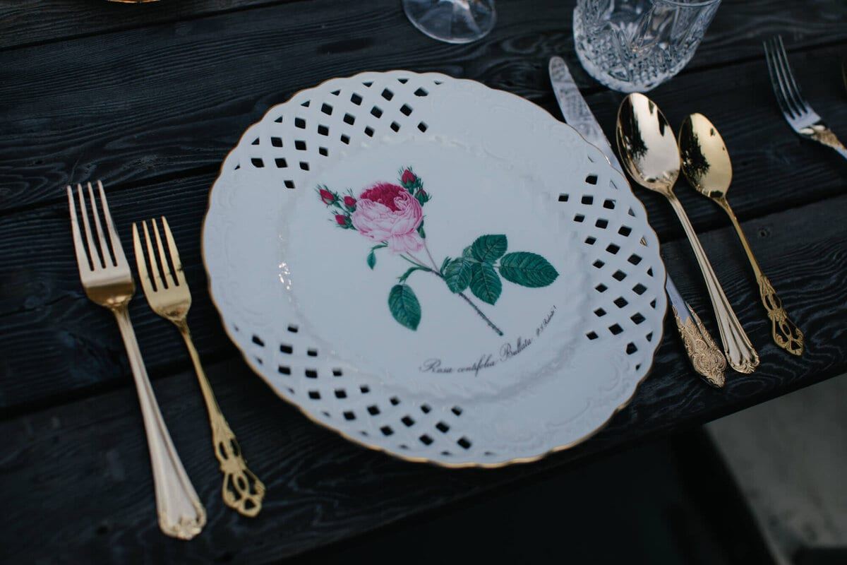 Lattice-edged botanical plate flanked by gold forks and spoons
