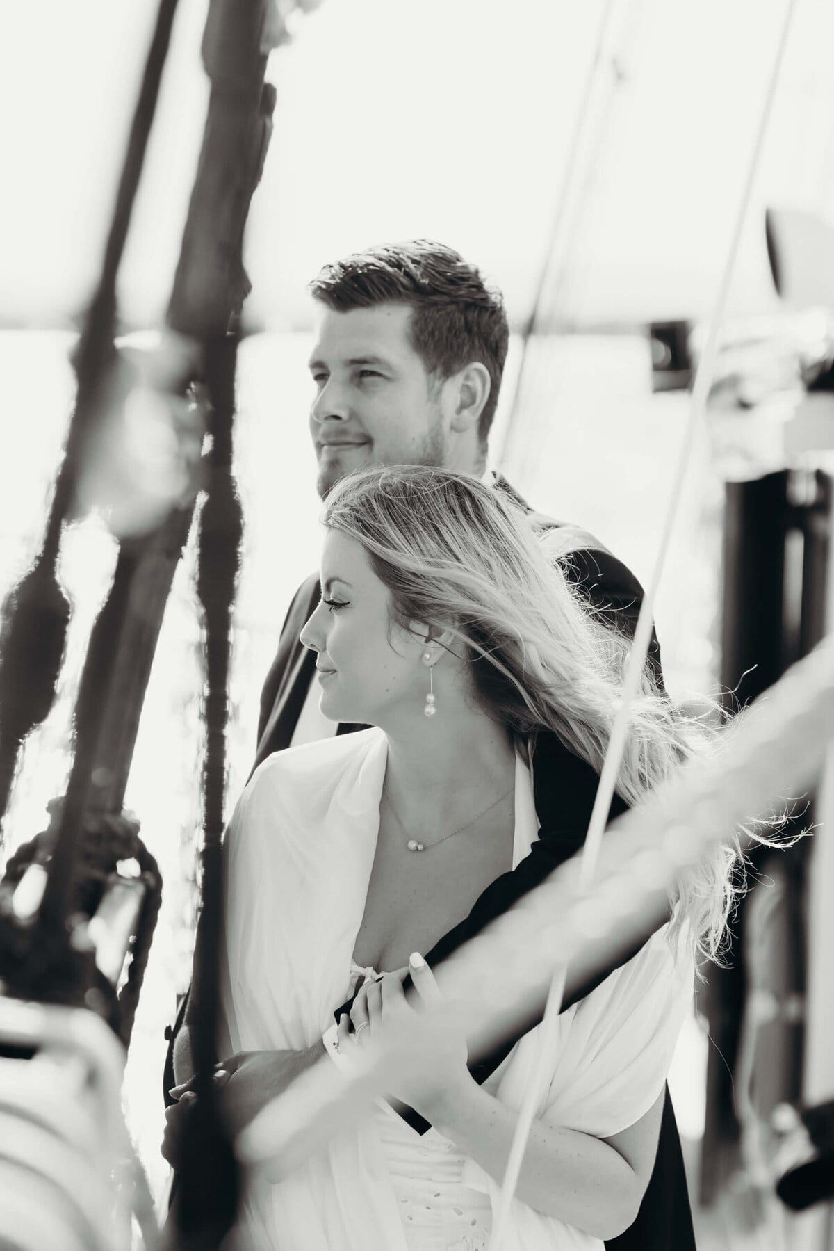 Groom holding the bride close, framed by rigging lines