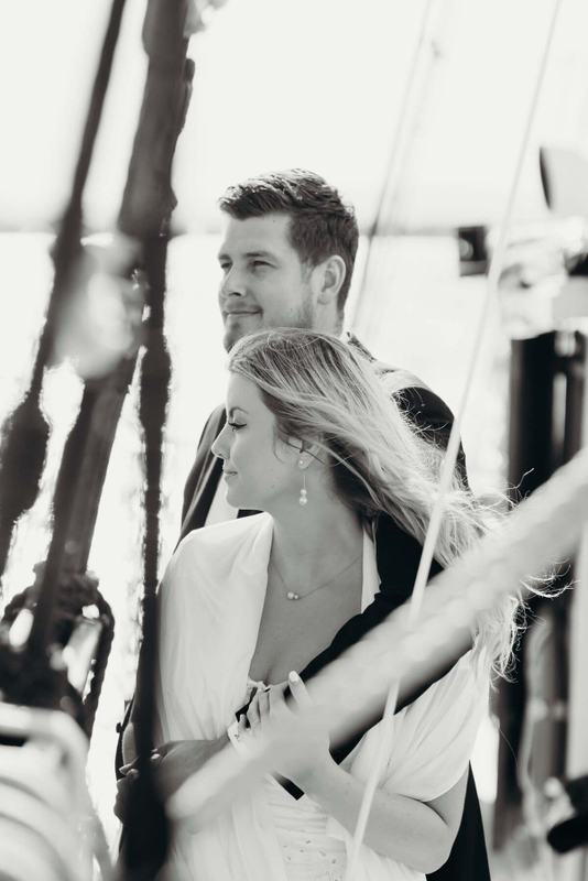 Groom holding the bride close, framed by rigging lines