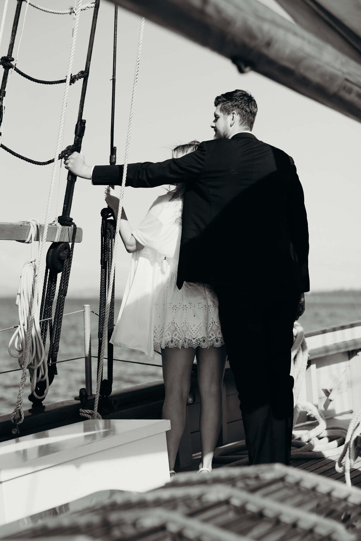 Groom's arm around the bride at the shrouds on deck