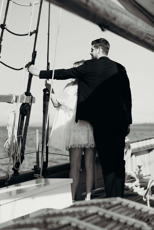 Groom's arm around the bride at the shrouds on deck