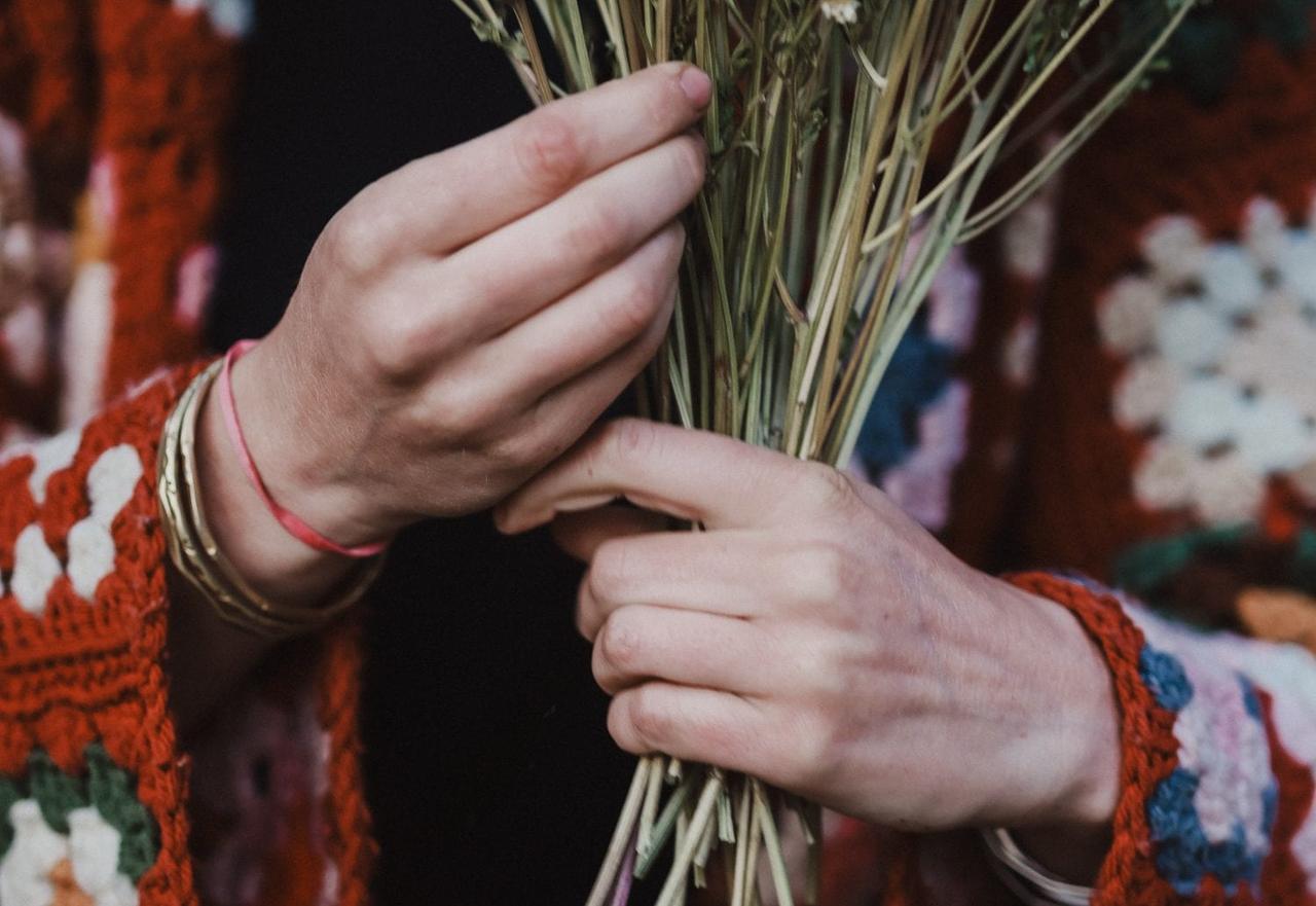 Two hands holding dried grass and straw bundles, suggesting wedding floristry materials on Salt Spring Island