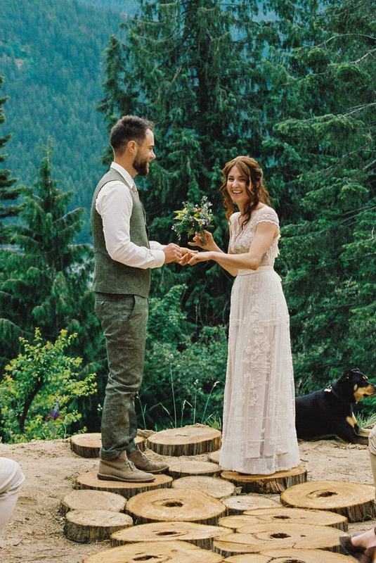 Groom passing a small bouquet to the bride at a mountaintop ceremony