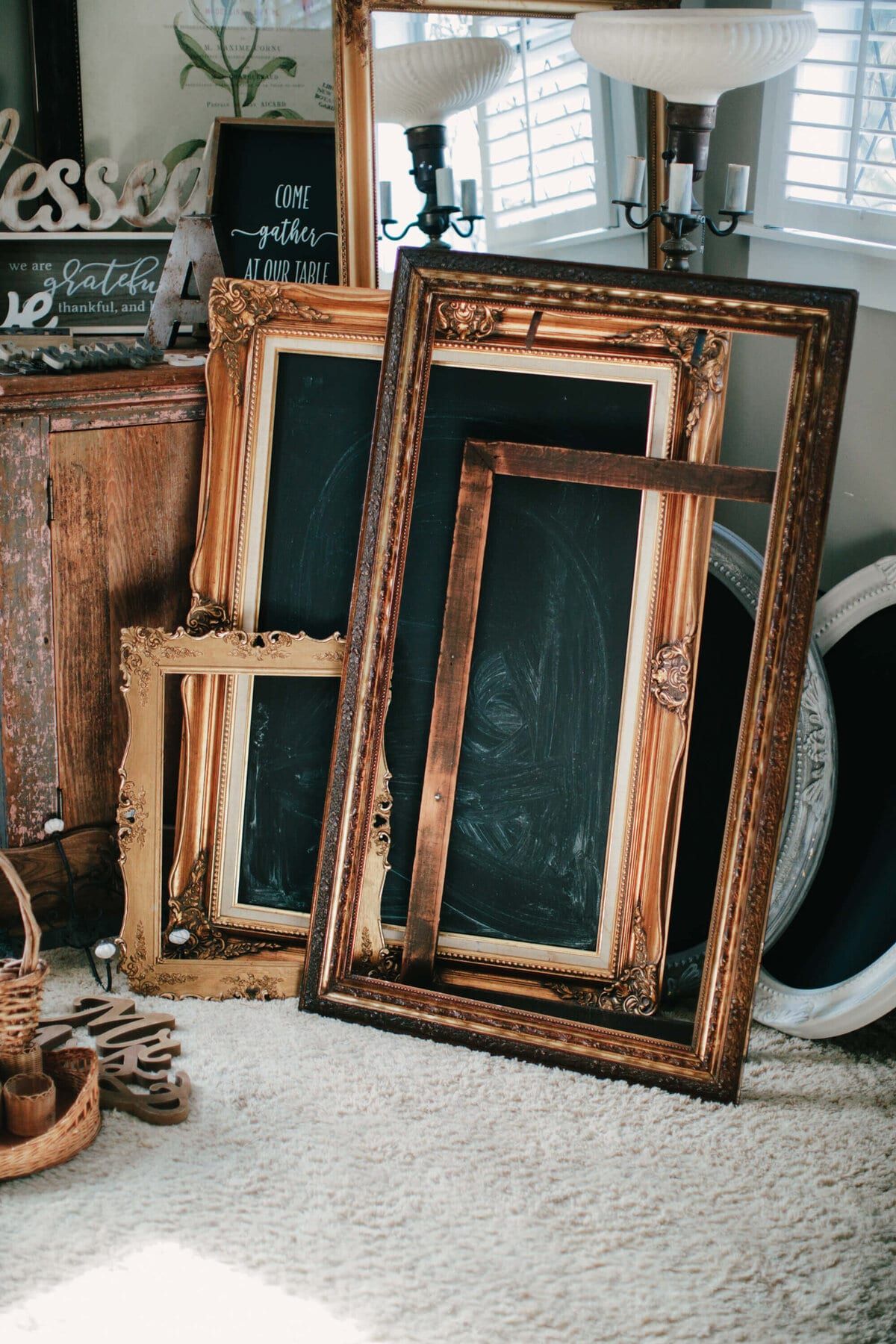 Ornate gold frames and chalkboards leaning in a stack