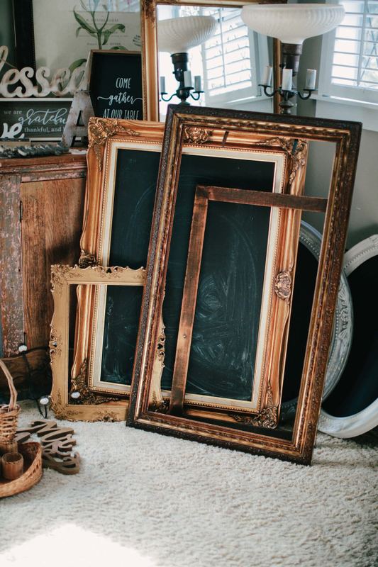 Ornate gold frames and chalkboards leaning in a stack
